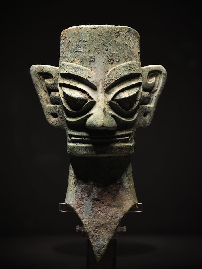 services-02 Ancient bronze Sanxingdui mask sculpture on a black background, exhibiting intricate craftsmanship.