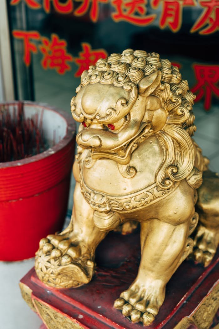gallery-4 Close-up of a golden lion statue in a Buddhist setting with red incense pot.