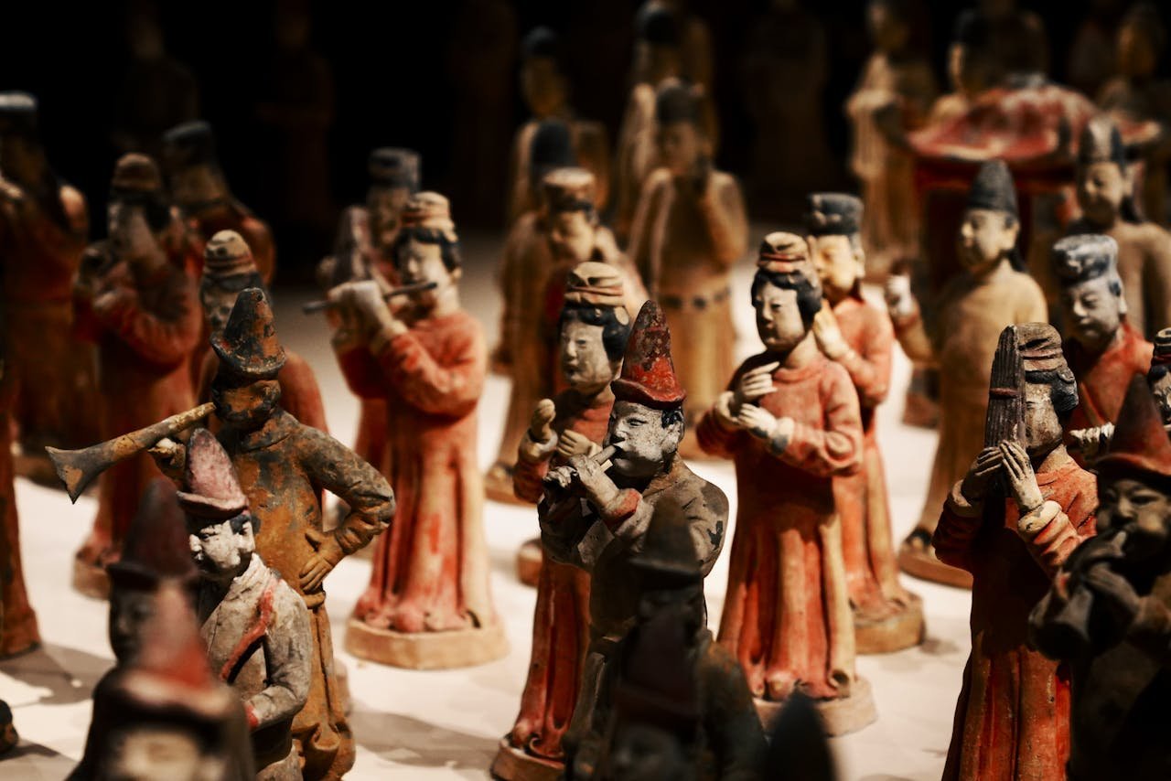 hero-img-01 Close-up of ancient Chinese terracotta musician figurines in traditional attire on display.