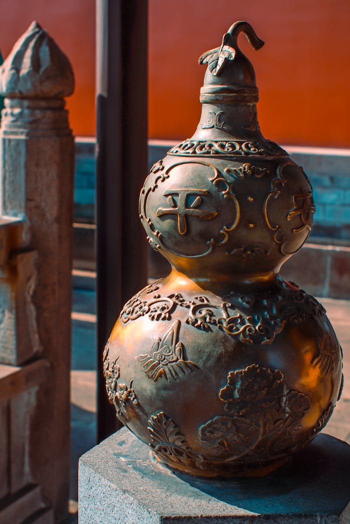 services-03 Decorative bronze gourd statue with intricate details lit by warm sunlight.