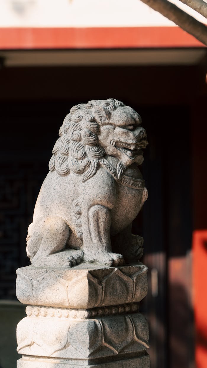 services-01 A carved stone lion statue outdoors, symbolizing protection and strength, with traditional Chinese architecture in background.